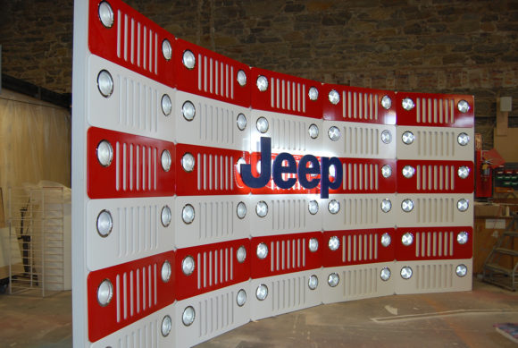 Jeep installation with red and white grill and lights on wall for event display